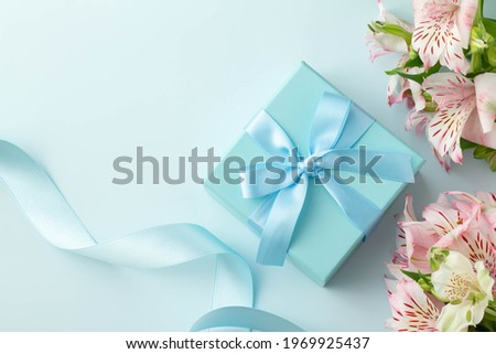 Light blue ribbon, gift box and plain background, pink alstroemeria gift image