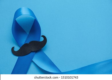 Light blue ribbon with mustache on blue background , Prostate Cancer Awareness, Movember Men health awareness, November Blue, International Men's Day - Powered by Shutterstock