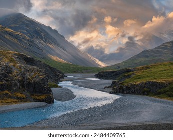 A light blue river winds through a dark gray mountain valley under a cloudy sky in Iceland. The image captures the stunning beauty of the Icelandic landscape. - Powered by Shutterstock