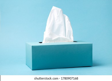 Light blue tissue box on blue background. Cold and flu concept. Minimal monochromatic composition.