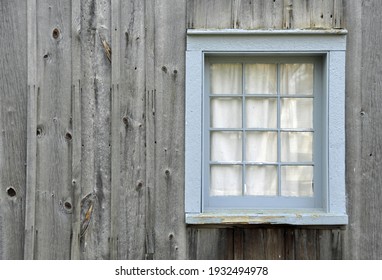 light blue vintage window pane on weather gray wooden siding 