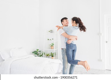 light and blur people, asian lover in white room, asian man carry asian woman, they hug and kiss together, they feeling happy and smile, honeymoon happiness