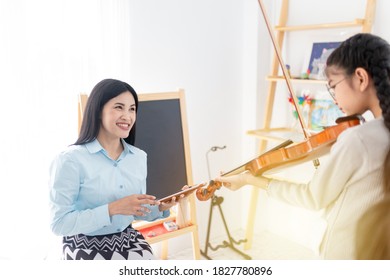 Light And Blur People, Close Up Teacher, Cute Asian Children Playing Violin With. Teacher, She Show Violin Skill And Present Melody And Song To Teacher, They Feeling Happy And Smile