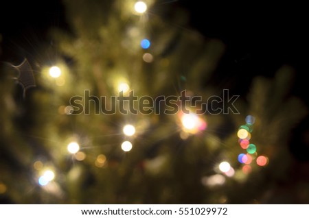 Light blurred multicolored lights on a real Christmas tree outside in the snow. Bokeh.
