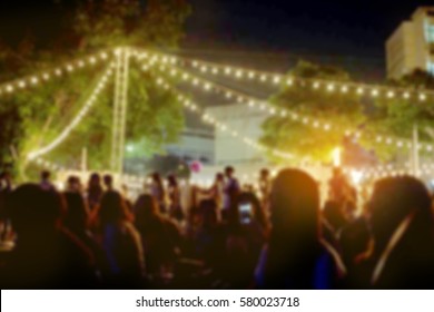 Light Bokeh Of People Sitting At Outdoor Concert Event.