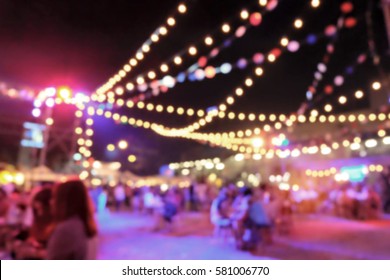 Light Bokeh Of People Sitting At Outdoor Concert Event.