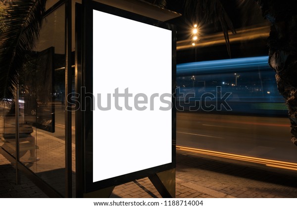 Light box\
advertising display with white blank space at bus stop at night.\
Mock-up design concept. Long\
exposure