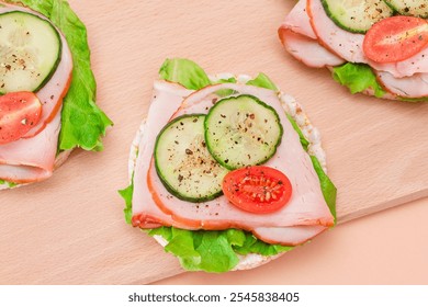 Light Breakfast. Quick and Healthy Sandwiches. Rice Cakes with Ham, Tomato, Fresh Cucumber and Green Salad on Wooden Cutting Board. Beige Background - Powered by Shutterstock