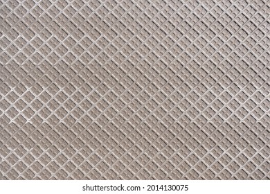 Light brown back side of a large tile with pattern of squares in close-up