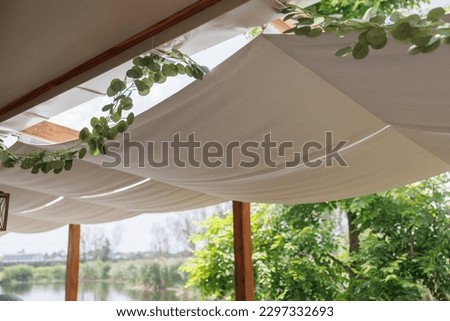 light brown fabric roof for sun protection. A hinged fabric roof, a summer patio, protection from the sun and heat, the interior of an outdoor cafe, white fabric on the ceiling.