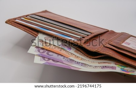 a light brown leather wallet with bank cards and a detailed close-up of new plastic GBP £ Sterling Ten and Twenty pound note currency