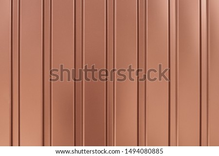 Light brown metallic striped surface. Gold background of metalline wall siding, cladding. Striated orange fence with shine, glitter. Reflecting metal convex texture.