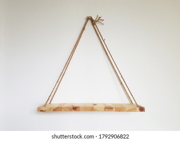 light brown wood shelf hanging on twine string rope on textured wall background
 - Shutterstock ID 1792906822