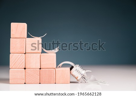 Light bulb falling down from the step stair wood blocks and broken, fail concept, bad idea cannot reach to the top stage, business going down