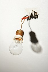 Light Bulb Hanging From Bare Wires With Shadow