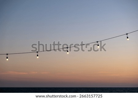 Light bulb, hanging string light with sunset beach view in the background