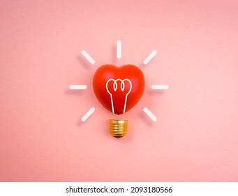 Light Bulb Icon On Red Heart Ball On Pink Pastel Background, Minimal Style. Love, Care, Sharing, Giving, Wellbeing, Inspiration, And Idea Concepts.