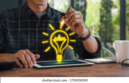 Light bulb idea concept or business ideas concept. Man is drawing a light bulb with the word idea on tablet computer. - Shutterstock ID 1739250590