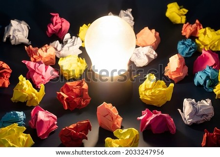 Light bulb iluminating in the middle of colorful crumpled papers. Idea concept Imagine de stoc © 