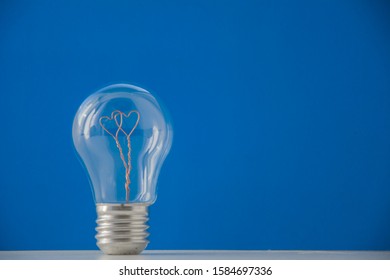 A light bulb inside which there are two hearts on classic blue background. Copyspace for text.