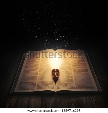 Light bulb lighting up an open bible on the dark. Imagine de stoc © 