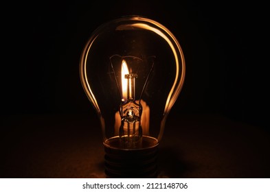 Light bulb with lit candle in background. Blackout city, electricity off, energy crisis or power outage, concept image. 
