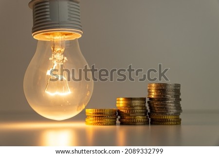 Light bulb on, with banknotes, coins and energy bill. Increase in energy and gas tariffs. Efficiency and energy saving.

