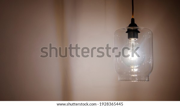 Light bulb on empty beige wall with\
copy space for inspiration or idea under light\
bulb.