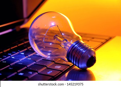 Light bulb on a laptop keypad with rainbow colors