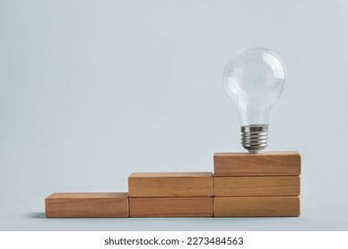 Light bulb on wooden stairs. Problem solving skill, creativity, innovation, brainstorming, critical thinking and root cause analysis concept. Saving money with energy