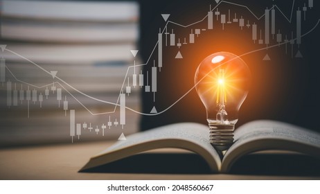 Light bulb and opened vintage book style vintage dark background concept and Stock market or forex trading graph and candlestick chart suitable for financial investment money, currency exchange. - Shutterstock ID 2048560667