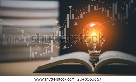 Light bulb and opened vintage book style vintage dark background concept and Stock market or forex trading graph and candlestick chart suitable for financial investment money, currency exchange.