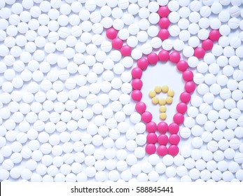 Light bulb with sparkle made by unique pink medicine pills among white ones background. Research and development in the pharmaceutical industry concept. Creative medicine idea. Copy space.