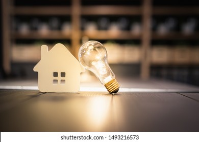 Light bulb with wood house on the table, a symbol for construction, Creative light bulb idea, power energy or business idea concept ecology, loan, mortgage, property or home. 
