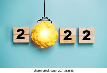 Light Bulb From Yellow Scrap Paper With 2022 Year On Wooden Cube Block For Happy New Year Idea And Creative Thinking Concept.