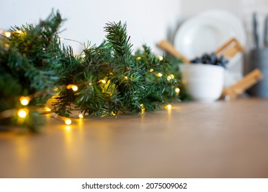 Light Bulbs In Coniferous Branches On Kitchen Table. Christmas Atmosphere.home Decor For Celebration