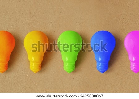 Light bulbs in different colors on recycled paper background - Concept of creativity and divergent thinking