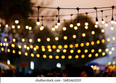 Light Bulbs On String Wire Against Sunset Sky In Party Even