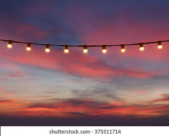 Light Bulbs On String Wire Against Sunset Sky