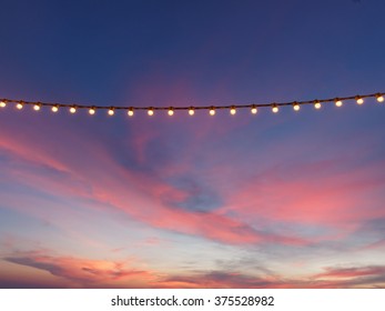 Light Bulbs On String Wire Against Sunset Sky 