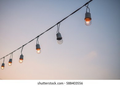Light bulbs on string wire against the sky. Party light. Good life or success concept.