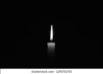 Light candle burning brightly in the black background. Candle flame. There's room for your text. Black and white photo. The concept of mourning, grief or sorrow. Located on the center of the shot. - Shutterstock ID 1293752755