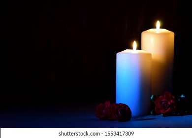 Light candles and roses on a dark background. Funeral memorial poster. Farewell condolences wallpaper. Posthumous burning candles. Mourning picture with place for text.