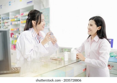 light and close up customer, asian female pharmacist explain about how to use drug with patient, she holding drug strip pack with her hand and talk with customer in drugstore