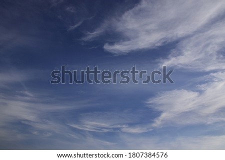 Light clouds in the deep blue sky. Typical signs of weather change. Natural background for graphic projects.