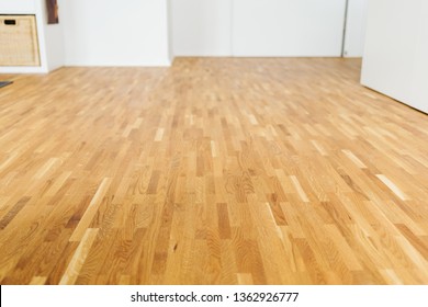 Light Colored Hardwood Floor In A Spacious Unfurnished Room With White Walls In A Low Angle Background View