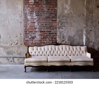 Light Colored Sofa In Industrial Space With Exposed Brick Wall.