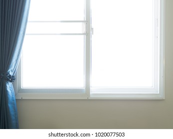 The light come in through open windows. Blue curtain are slided to edge of window. Interior design. 