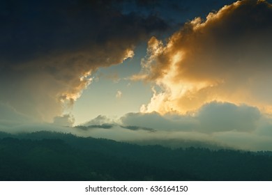 Light coming through window of clouds from setting sun, over Himalayan Mountain peaks. Dramatic cloud formation with sunset colours over Indian Mountain peaks.