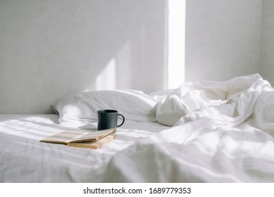 Light cozy bedroom, Coffee or tea cup and an open book on the bed.